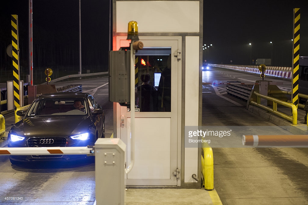 A cashier collects payment for a road toll from a motorist at a toll booth exit on the A2 highway linking Berlin and Warsaw in Tarnawa, Poland, on Friday, Dec. 13, 2013. Autostrada Wielkopolska SA, founded by the country's richest man Jan Kulczyk, wants to refinance euro-denominated loans taken in 2000 to fund construction, and may sell a portion of the bond to the European Bank for Reconstruction and Development, the World Bank and state-owned Bank Gospodarstwa Krajowego. Photographer: Bartek Sadowski/Bloomberg