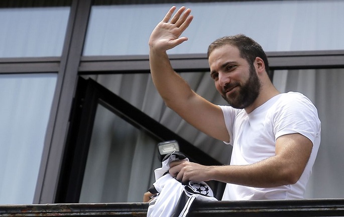 Juventus' forward Gonzalo Higuain from Argentina waves from the Juventus' headquarter in Turin on July 27, 2016. In the most unlikely move of the Serie A summer transfer period, Higuain ended his fairytale three-year spell with Napoli on Tuesday when he agreed to a record five-year deal with the Italian champions that is expected to earn him 7.5m euros a year. / AFP PHOTO / MARCO BERTORELLOMARCO BERTORELLO/AFP/Getty Images